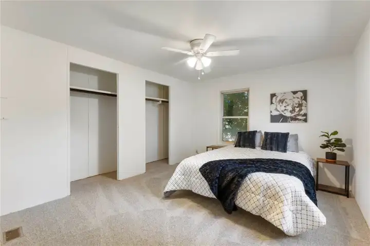 Primary bedroom with double closets, ceiling fan & attached three quarter bathroom.