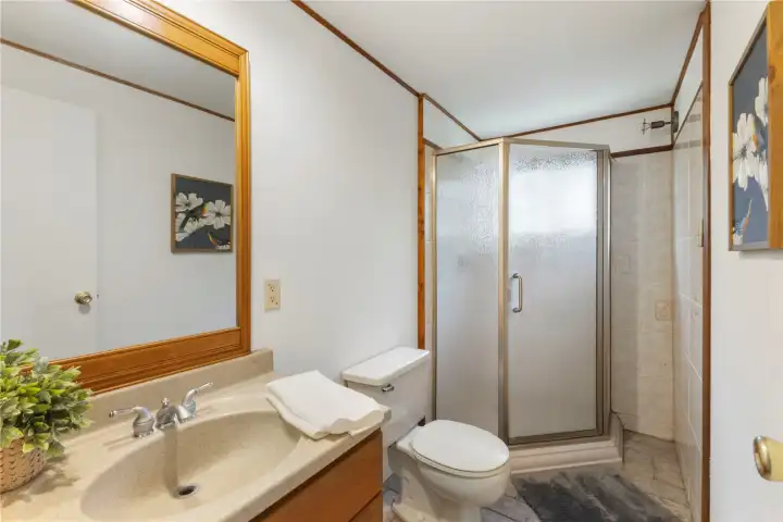 Three-quarter bath off primary bedroom with updated vanity and tile flooring.