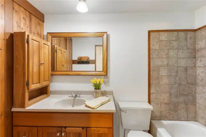 Full bathroom off second primary bedroom. Tile tub surround and flooring.