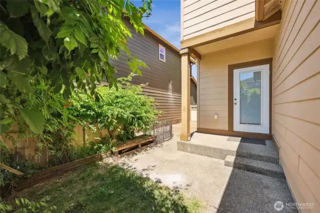 Cozy back patio tucked behind lush shrubbery for added privacy.