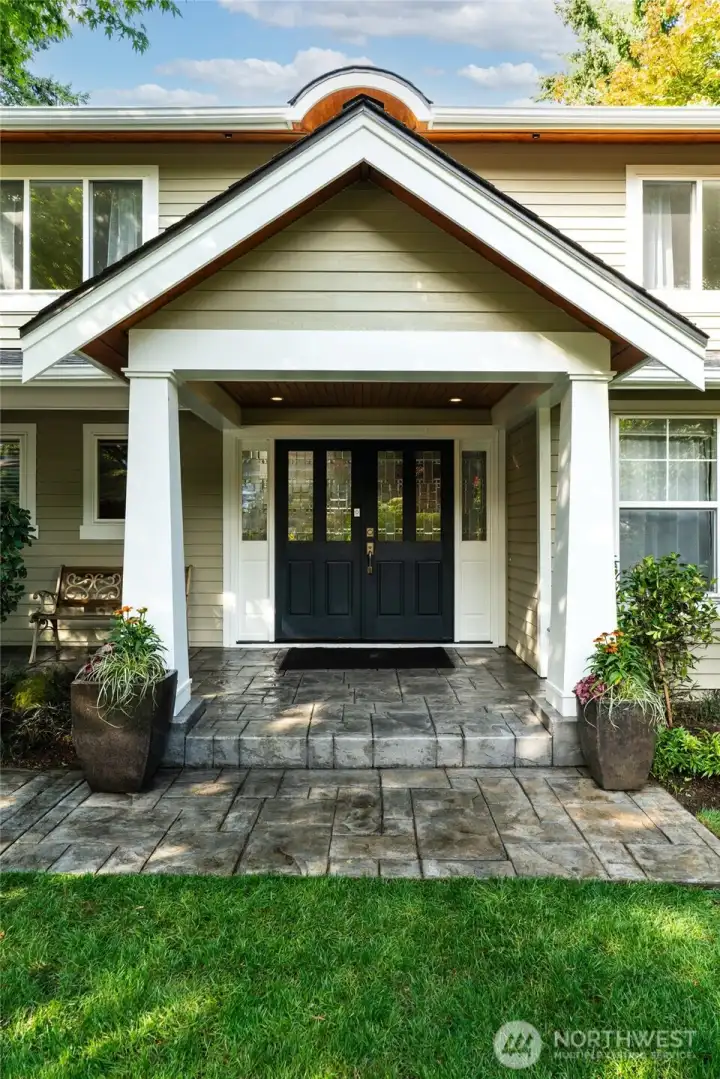 Beneath a welcoming covered front porch, accented with a rich cedar-lined ceiling, stately double doors invite you inside