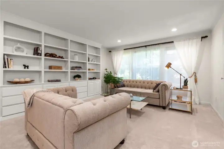 A refined living room features custom, expansive bookshelves and oversized front window