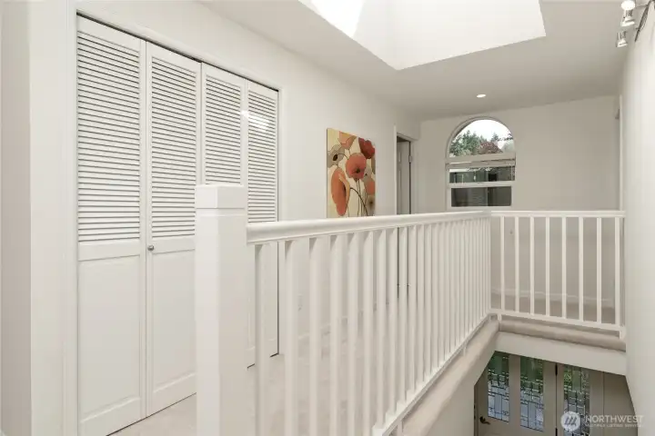 The open spindle hallway and large stairwell skylight allow natural light to connect the upper and lower levels