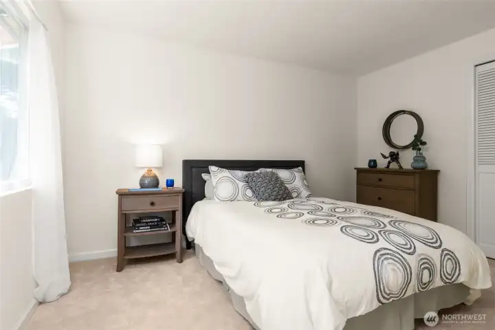 Bright upstairs bedroom with new carpeting, fresh paint, and space for a queen bed
