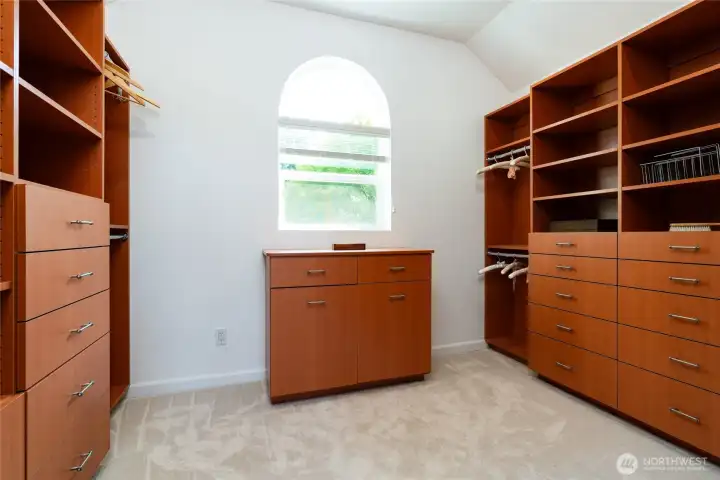 The primary bedroom walk-in closet features custom organizers and a window for natural light
