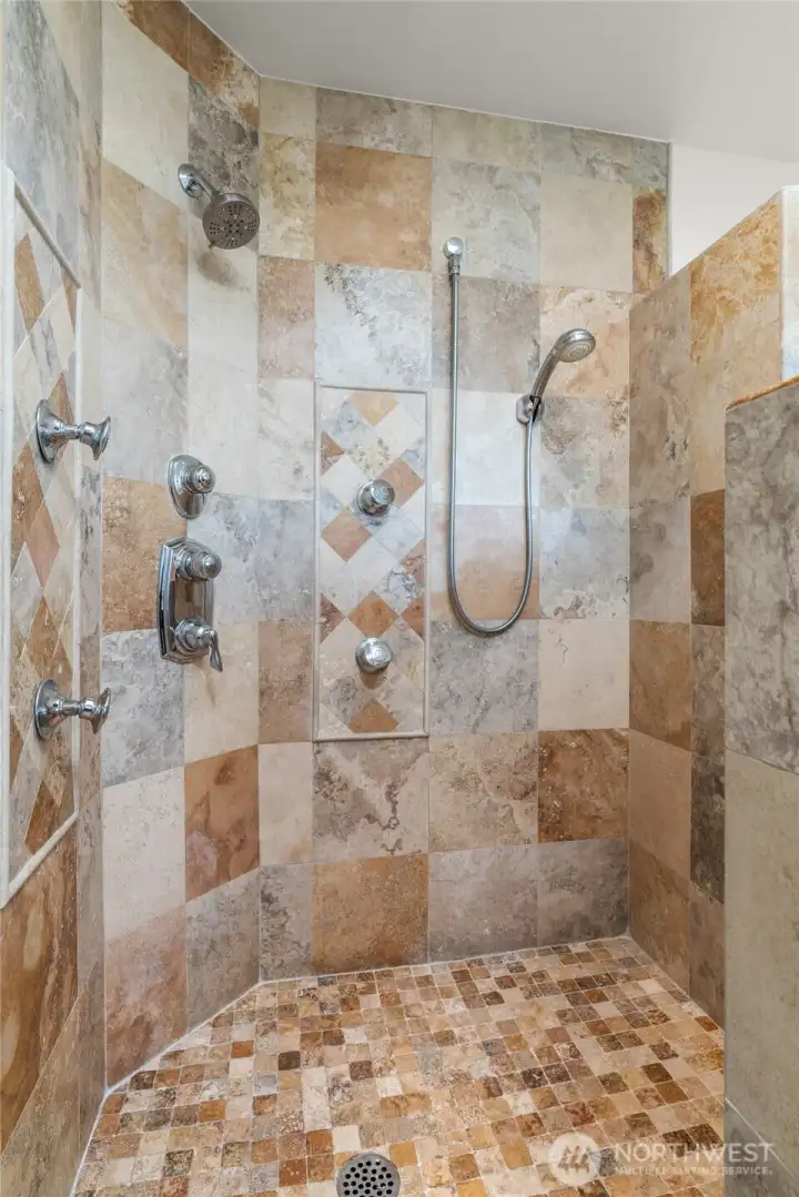 Tiled walk-in shower in primary bath, offers four shower heads for the ultimate shower experience