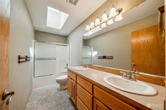 Upstairs main hall bathroom w/ double sinks, skylights & glass shower doors.