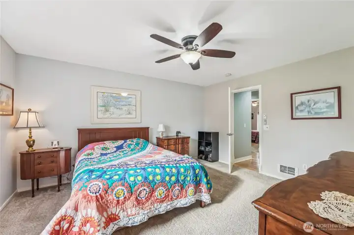 Primary bedroom has a walk in closet, ceiling fan and double doors.