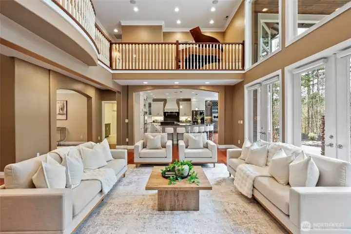 Open concept living room (off the kitchen) with dramatic two story windows and a series of French doors opening to the expansive backyard.