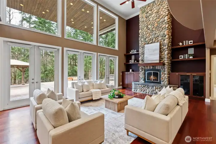 Living room with dramatic two story windows, a floor to ceiling gas river rock fireplace, and a series of French doors opening to the expansive backyard. A true Pacific Northwest oasis.