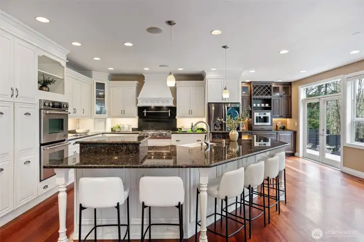 Chef's kitchen with eight person seating, granite countertops, stainless steal appliances, double ovens, 6 burner gas stove, farmhouse and beverage sinks, abundant storage, espresso bar, and French doors that lead to the back patio. Perfect for entertaining.