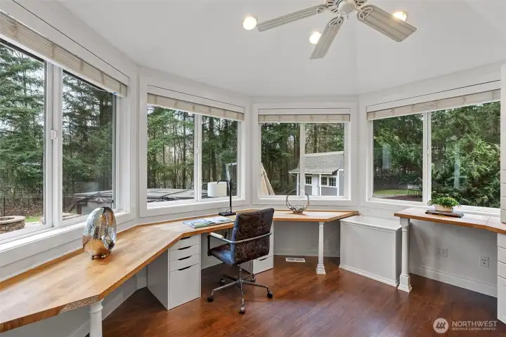 Office with wrapped around windows that flood the space with natural light and overlooks the serene backyard.