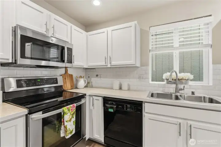 Chefs will delight in this functional kitchen with a center island with additional cabinetry space, stainless refrigerator & oven range and a newer 2022 microwave and shaker cabinetry and full-height subway tiled backsplash.