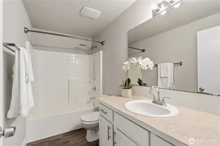 The full guest bathroom with ample counter space and shaker cabinetry is conveniently central to both bedrooms and the loft area.