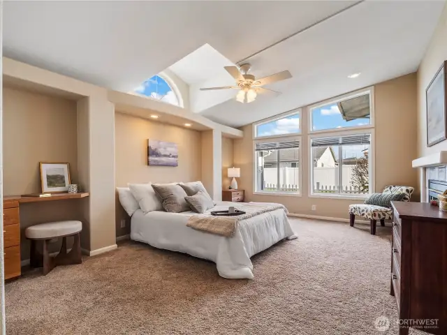 The spacious primary bedroom with ensuite features vaulted ceilings and coxy fireplace.