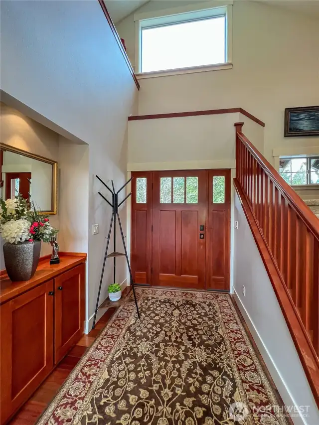 Entry opens up to high vaulted ceilings and warm custom woodwork.