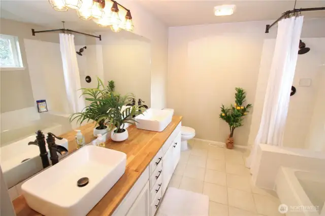 Stunning primary bathroom with vessel sinks, a shower, and a tub.