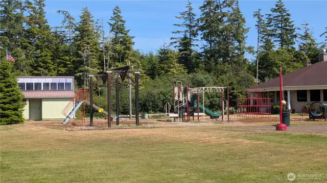 Lush greenery surrounds the Sunset Sands community playground, where kids can swing and climb just steps from the well-kept clubhouse and public restrooms—a welcoming hub for outdoor fun and neighborhood gatherings.