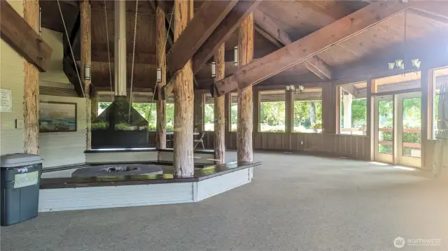 Warm and welcoming, the Sunset Sands Clubhouse boasts a striking central firepit framed by rich wood beams and soaring ceilings. Sunlight pours through expansive windows, highlighting the rustic architecture and cozy charm—an ideal gathering place for community connection or peaceful reflection
