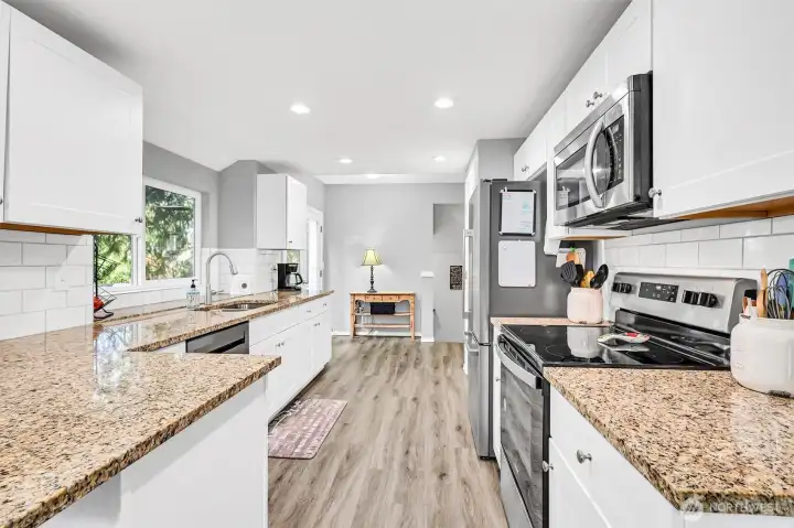 Gorgeous updated kitchen with granite counters, undermount kitchen sink, full height tile backsplash, stainless steel appliances & lots of cabinets
