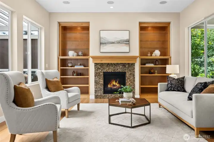 Living rooom with gas fireplace adorned with custom built-in complete with glass shelves, lighting and view out to both covered patios