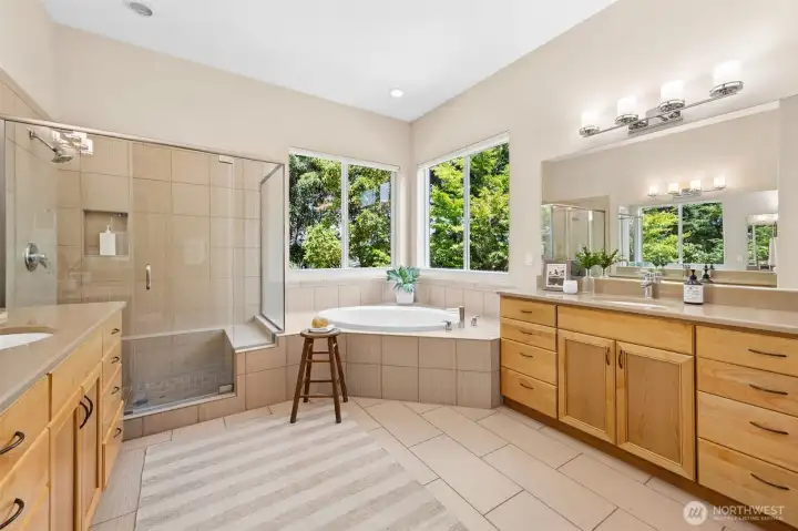 Primary bathroom with 2 large vanities, adorned with quartz counters and soaking tub with views of greenbelt. Window have top/bottom shades for adjustable light