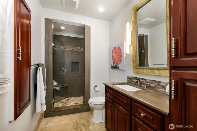 Shower bath on main floor with pebble floor and built-in seat. Pantry cabinet for storage
