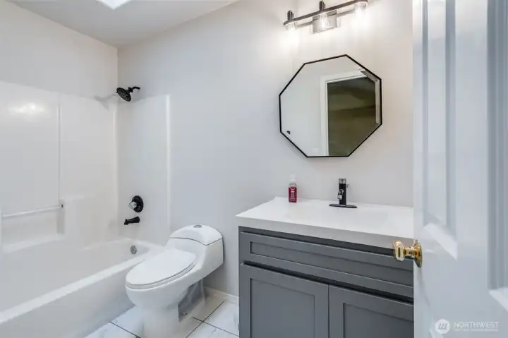 The full secondary bathroom is brightened by a skylight, providing wonderful natural light. This highly functional space features a convenient bathtub/shower combination, perfect for serving the two upstairs bedrooms.