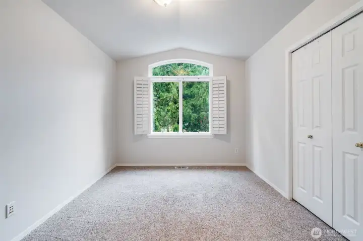 This bright secondary bedroom is situated near the front of the home on the upper level. It offers ample closet space and generous natural light, making it a perfect guest room or child's bedroom.
