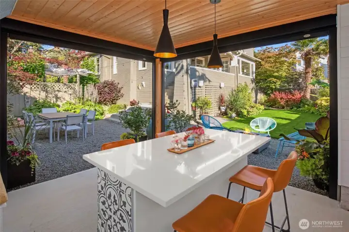 Covered pavilion featuring a built-in grill, gas heater, and dining area for year-round entertaining.