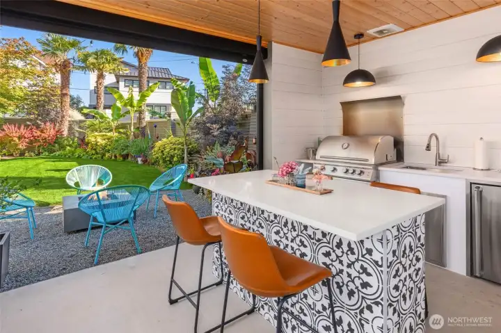 Covered pavilion featuring a built-in grill, gas heater, and dining area for year-round entertaining.