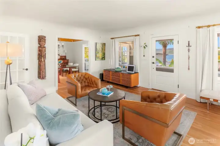 Main floor features a gracious living room opening to a covered front porch overlooking   lush gardens and water views.