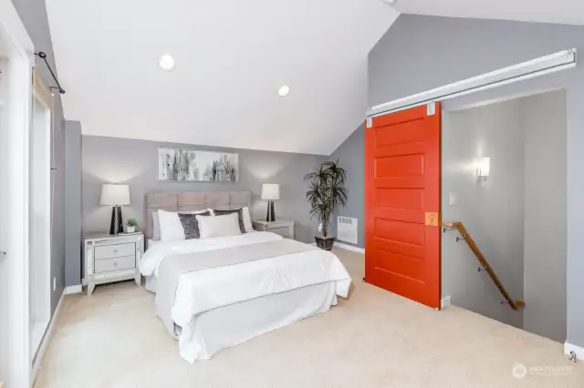 Spacious Primary bedroom with vaulted ceiling and modern sliding barn door.