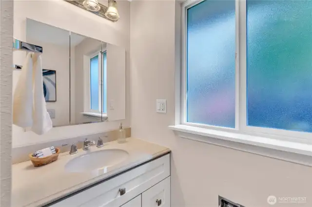Hall Bath with a multi-mirror medicine cabinet over the vanity.  Fan and a window for cross ventilation.