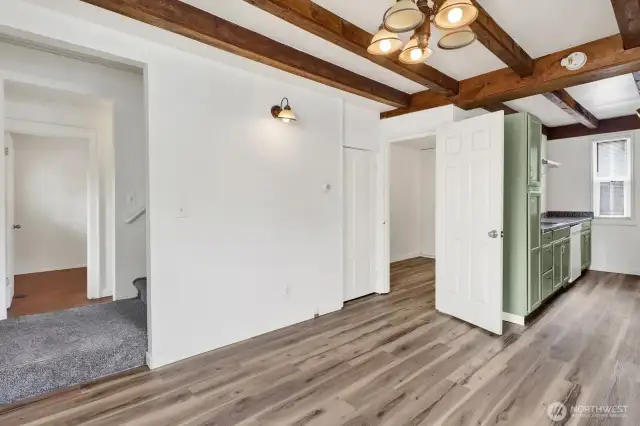 Living room with wood beams and new LVP Flooring open to the kitchen.