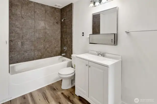 Main floor bath with tub/shower with tile surround, and new LVP flooring. and laundry hookup on the other side of room, no washer or dryer included with this home.