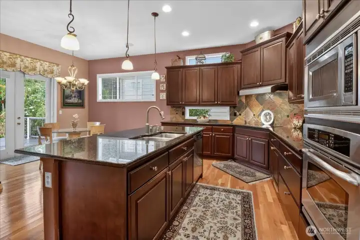 Spacious and warm, you'll enjoy preparing snacks and meals in this well equiped Kitchen with SS Appliances, Pendant lighting over an occomodating center Island, Pullouts with no center stiles, recycle & refuse bins, granite counter-tops and full-height backsplash and French Doors with retractable Screens along the breakfast Nook.