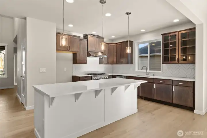 Kitchen with hardwood floors, quartz slab island, room for barstools. *Actual Kitchen will feature different cabinet colors.