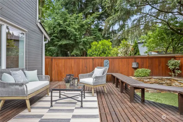 This spacious backyard deck offers a perfect retreat for outdoor relaxation and entertaining, surrounded by lush greenery and privacy fencing. Enjoy serene afternoons and cozy evenings in this beautifully designed outdoor space. Notice the beautiful built-in, raised planting beds in stack rock!