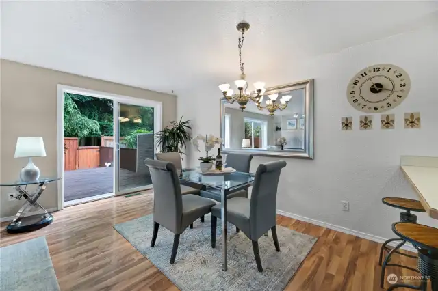 The dining area features elegant lighting, and an included large mirror. The sliding door opens to a spacious deck. Perfect for entertaining, this area seamlessly blends indoor comfort with outdoor charm.