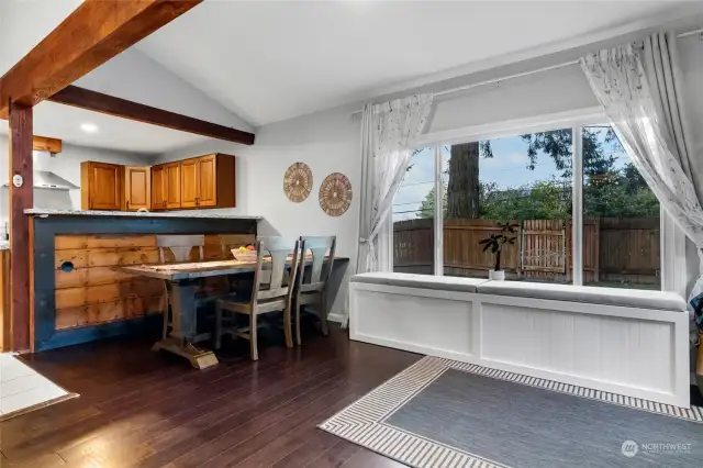 Kitchen looks out to dining and living room and bench seating with picture window