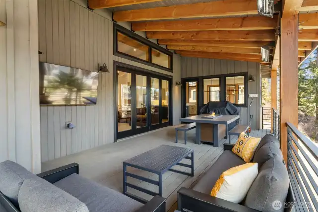 Outdoor deck with heaters, fire table, and tv.