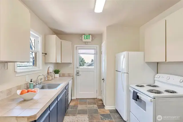 Kitchen area with stove, dishwasher and refrigerator. Entry to back patio and deck