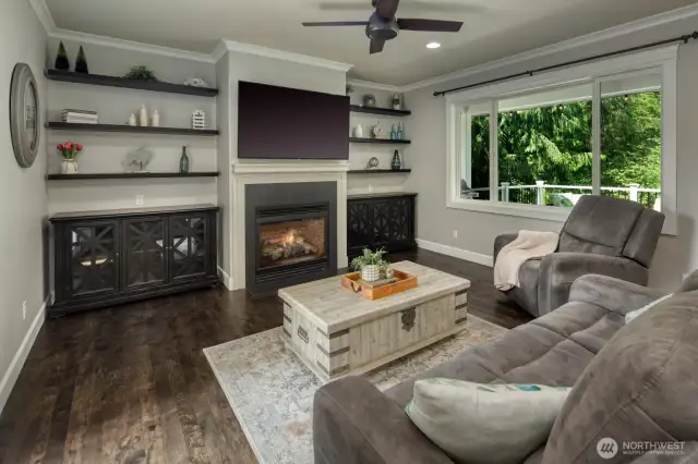Cozy up in this stylish Family Room featuring a gas fireplace with tile surround, custom built-ins, large picture window with views and easy access to the patio/deck —an inviting space adjacent to the kitchen for everyday living or entertaining.