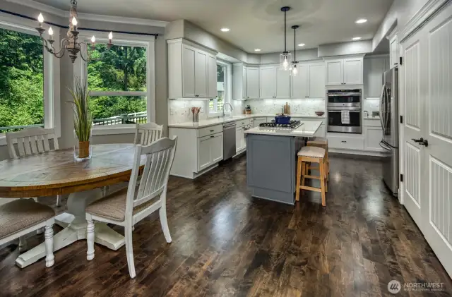 Enjoy cooking and gathering in this bright, beautifully updated kitchen featuring quartz countertops, a spacious island with bar seating, stainless steel appliances, and custom cabinetry  and rich hardwood flooring—all set against a backdrop with views to the fully fences landscaped private backyard.