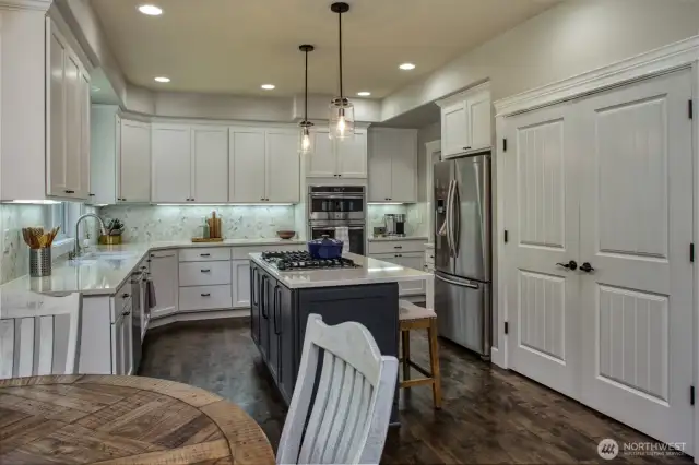 This chef-inspired kitchen features crisp white cabinetry, a stylish tile backsplash, stainless steel appliances, and a contrasting center island with gas cooktop—perfectly blending form and function.