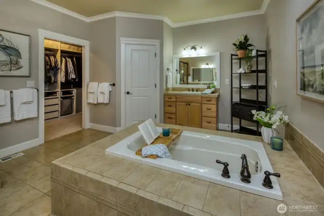 Unwind in the spa-inspired primary bathroom featuring a soaking tub with tile surround, dual vanities, ample storage, and a walk-in closet—designed for both comfort and function.
