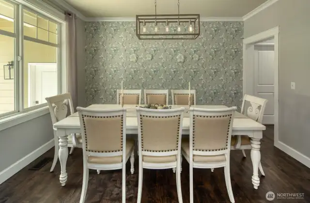 Elegant and inviting, the formal dining room features rich hardwood flooring, designer wall-covering, and a statement light fixture—perfect for hosting dinner parties or enjoying quiet, intimate meals at home.