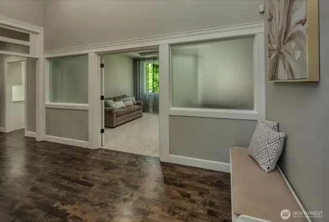 This cozy secondary living flex space features a classic gas fireplace framed by elegant columns, carpeting, and views to the expansive private back yard—ideal for relaxing, reading, or hosting intimate gatherings in comfort.