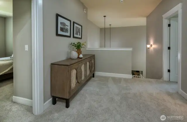 The upper landing connects the second-floor bedrooms and bath, tasteful accents, and open sightlines to the entry below. Conveniently accessible from both the main staircase and a second stairway off the family room and kitchen, it offers seamless flow throughout the home.